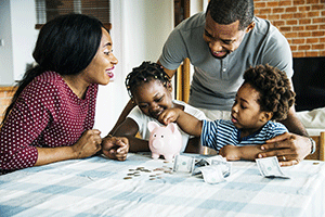 smiling family putting coins in a piggy bank