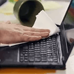 man wiping spilled coffee from laptop