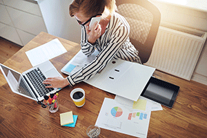 business woman at desk with computer multi-tasking